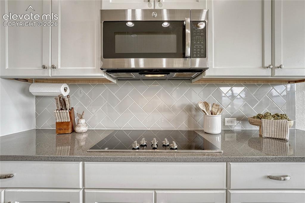 Image 12 of 50: A close-up of the sleek glass cooktop reveals the sophisticated style of th