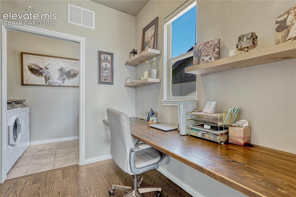 Image 16 of 50: A highly functional main-level study nook is tucked away with custom floati