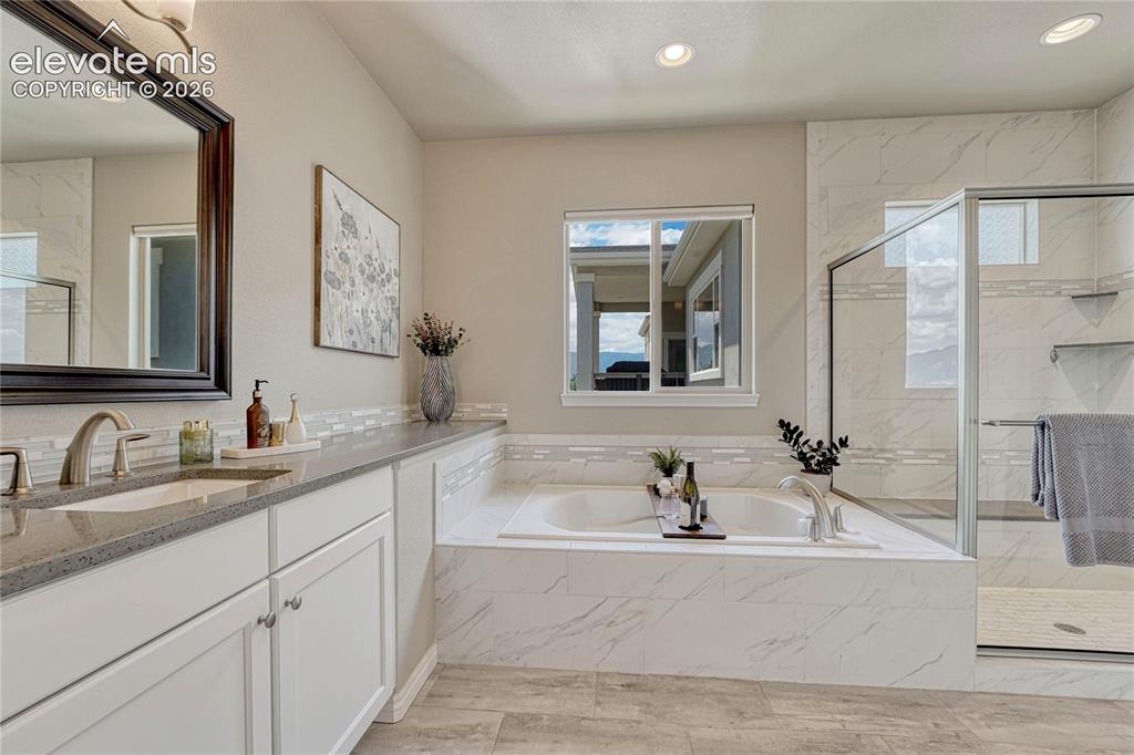 Image 22 of 50: The spa-like en suite primary bathroom features a deep soaking tub surround