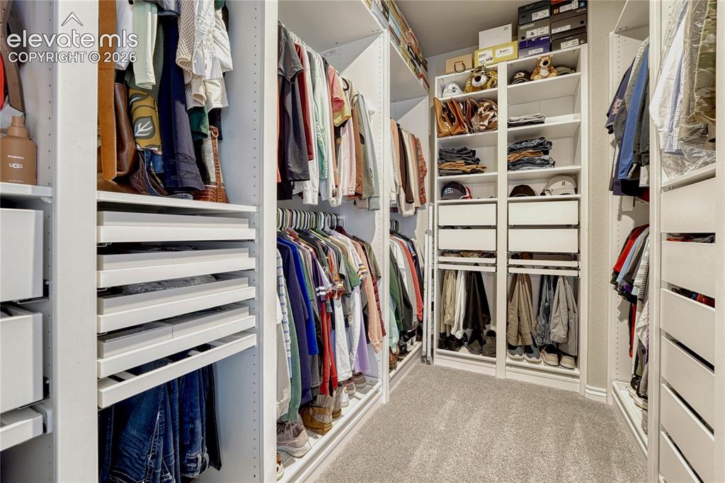 Image 24 of 50: The custom-designed primary walk-in closet is fully loaded with a professio