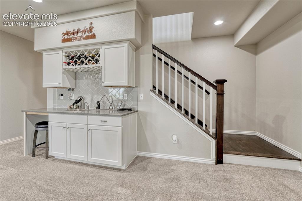 Image 25 of 50: The finished basement features a stylish built-in wet bar complete with whi