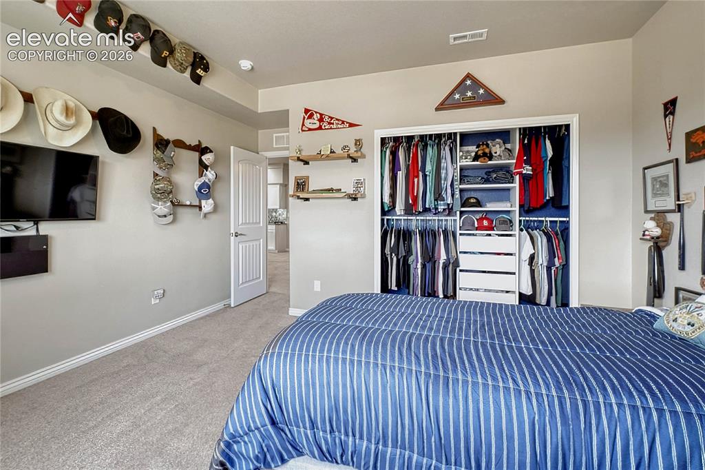 Image 39 of 50: This bedroom also enjoys an organized walk-in closet with custom built-in w