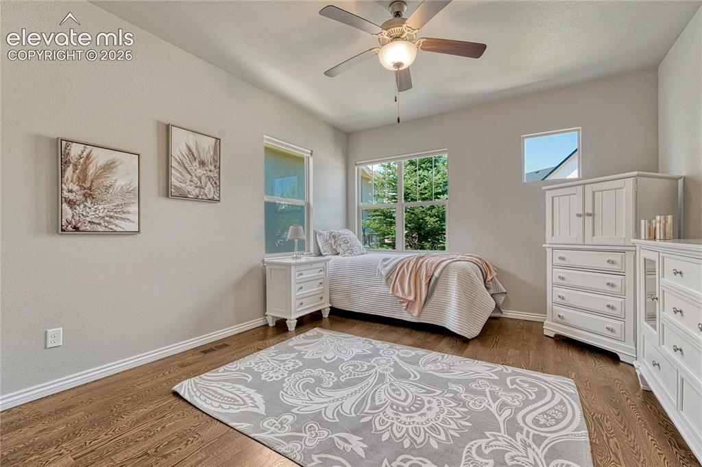 Image 4 of 50: The main-level guest bedroom boasts pristine oak hardwood floors and large