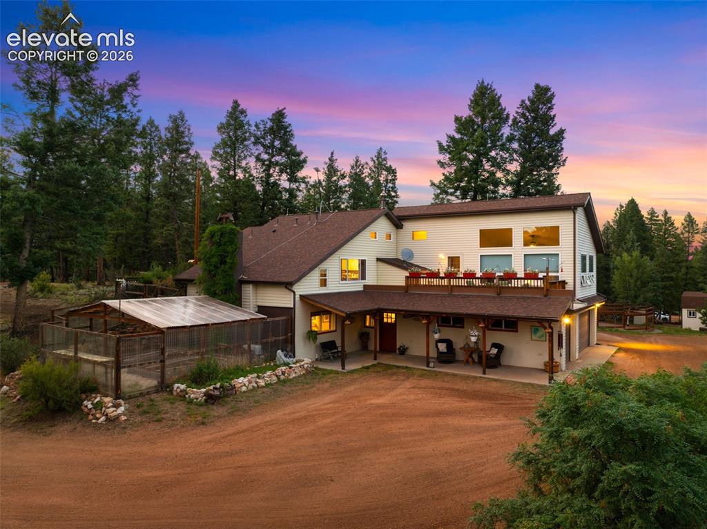 Caption: Expansive outdoor living with a large upper deck, covered patio, greenhouse and enclosed garden area