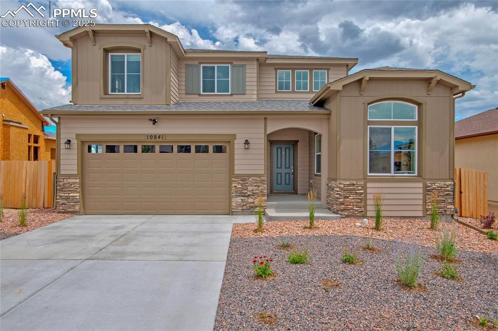 Caption: View of front of home featuring stone siding, a garage, driveway, and roof with shingles