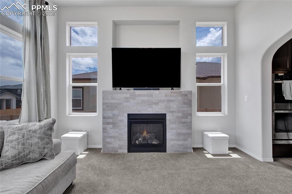 Image 14 of 41: Living area featuring arched walkways, carpet, and a glass covered fireplac