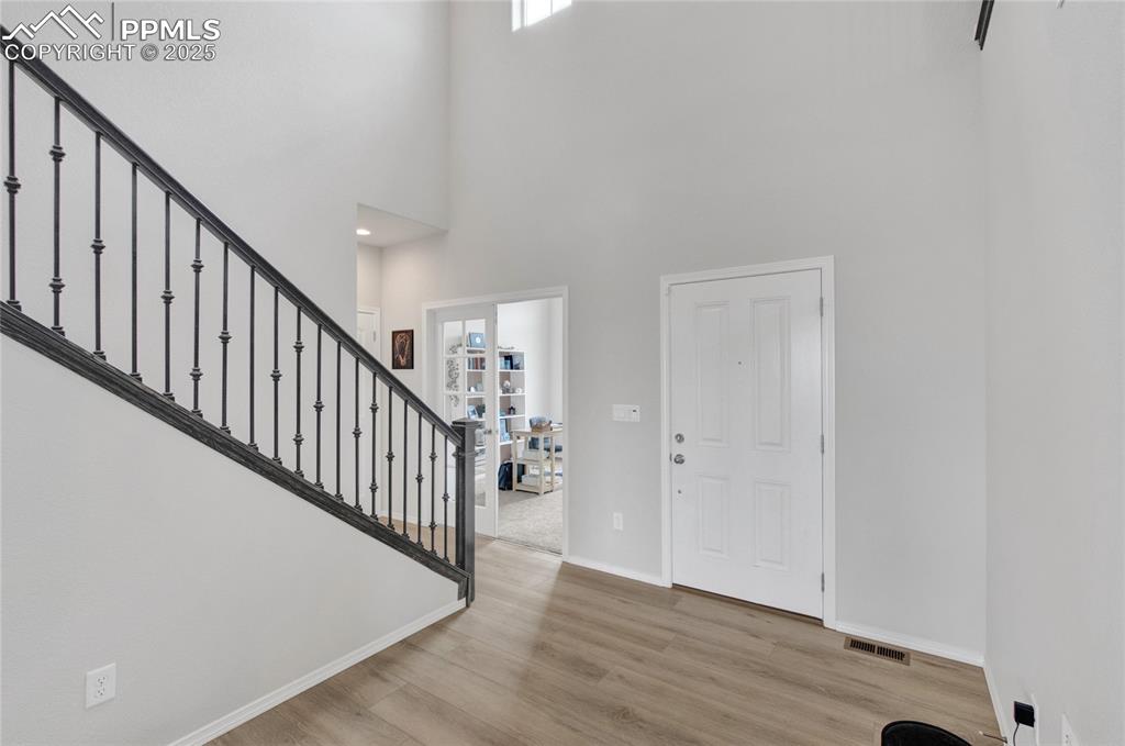 Image 15 of 41: Entrance foyer with wood finished floors, stairs, and a towering ceiling