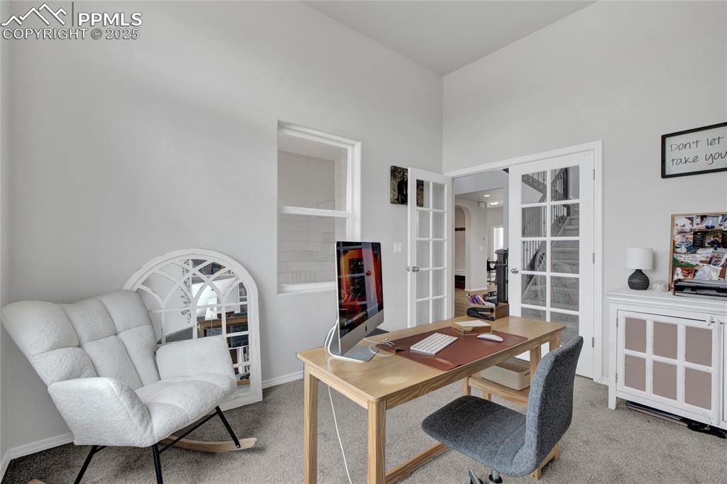 Image 17 of 41: Carpeted office featuring french doors and arched walkways