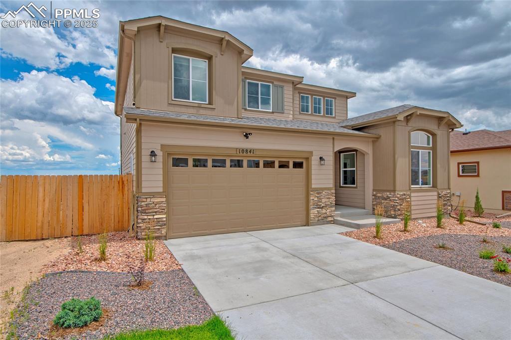 Image 2 of 41: View of front of home featuring stone siding, concrete driveway, a garage, 