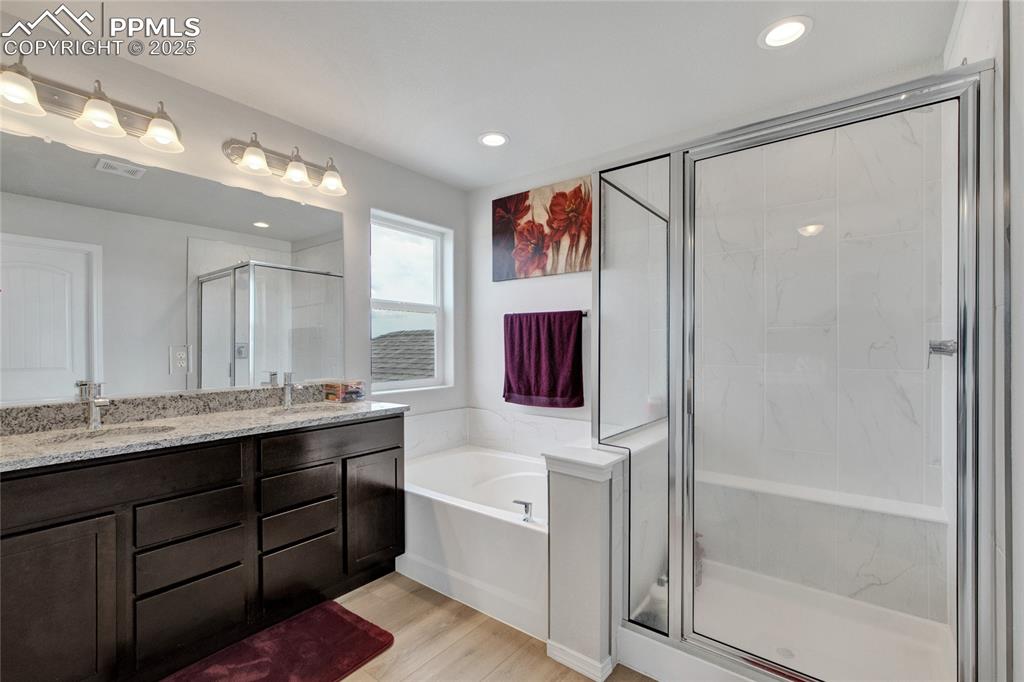 Image 24 of 41: Bathroom featuring a stall shower, double vanity, a garden tub, wood finish