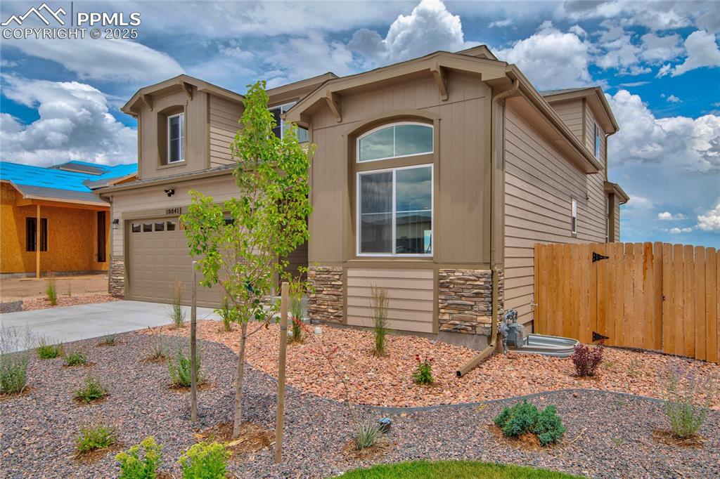 Image 3 of 41: View of front of property with stone siding, concrete driveway, and an atta