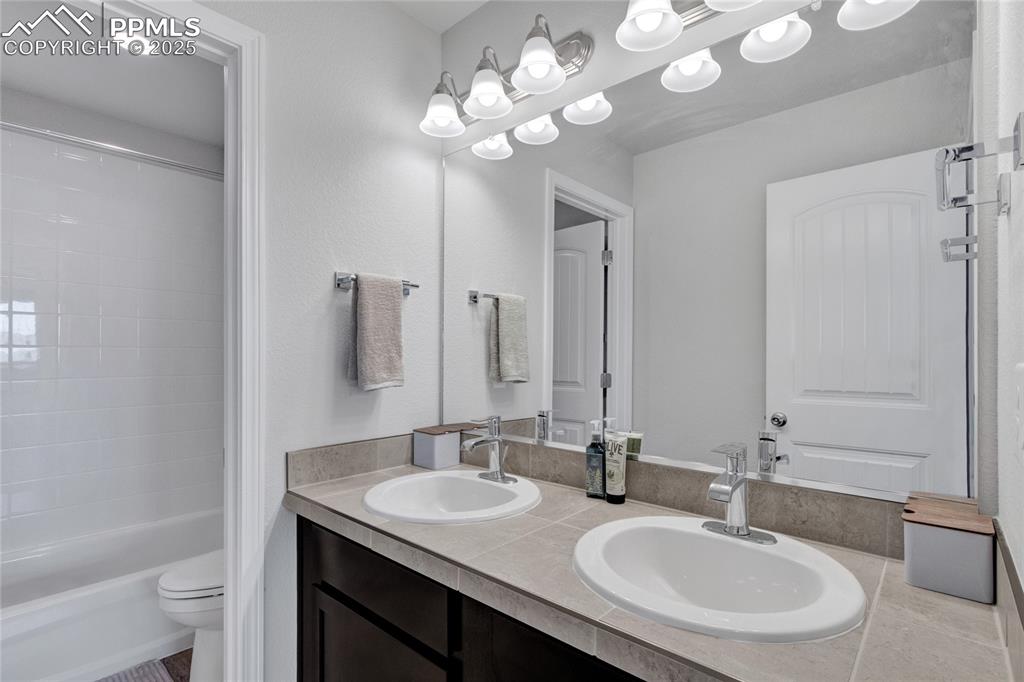 Image 32 of 41: Bathroom featuring double vanity and shower / washtub combination