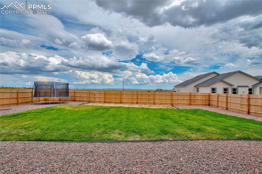 Image 39 of 41: Fenced backyard with a trampoline
