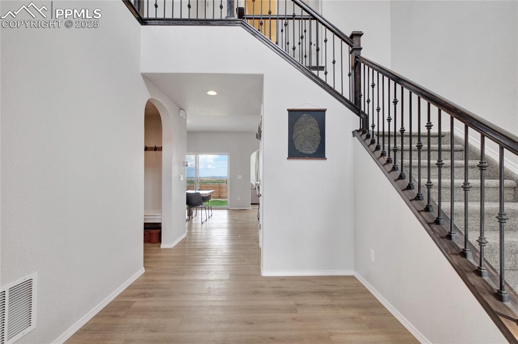 Image 5 of 41: Staircase featuring arched walkways, a towering ceiling, wood finished floo