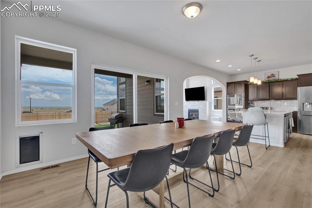 Image 8 of 41: Dining space with a glass covered fireplace, light wood-style floors, reces