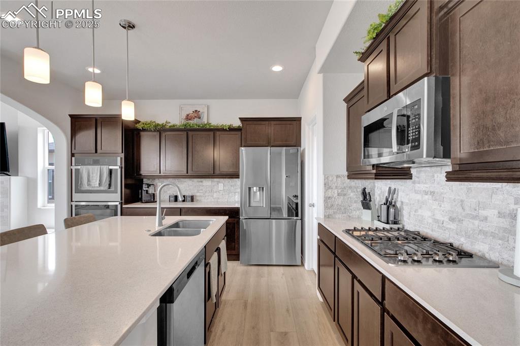 Image 9 of 41: Kitchen featuring light wood-type flooring, dark brown cabinets, stainless 