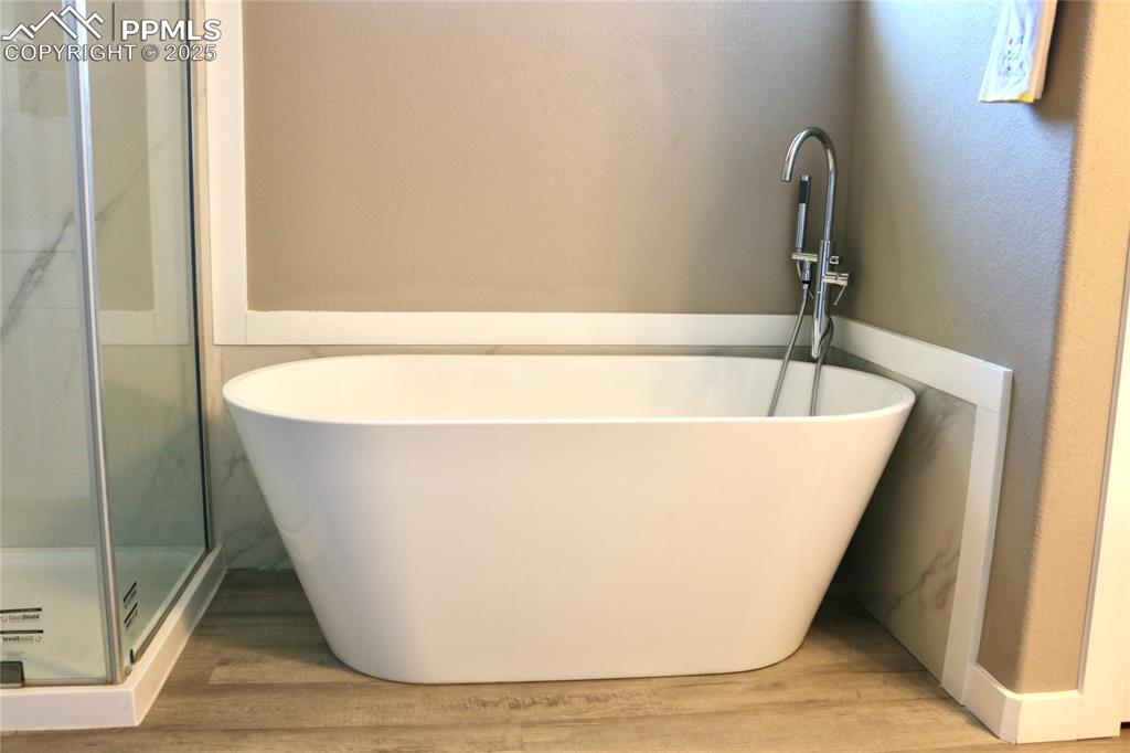 Image 10 of 28: Bathroom with a freestanding tub, wood finished floors, and a stall shower