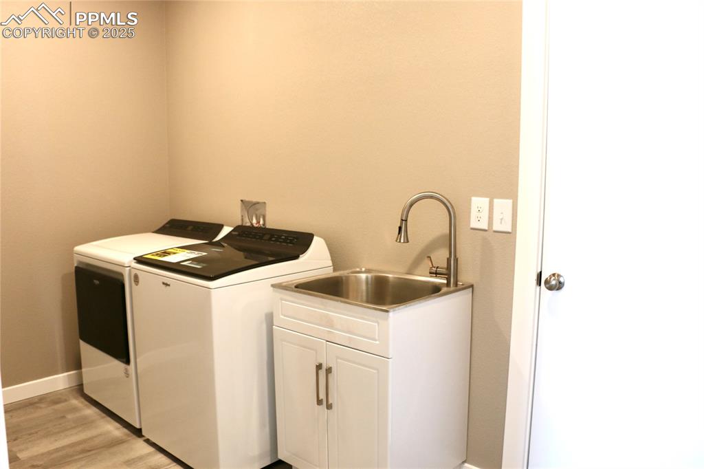 Image 16 of 28: Laundry area with light wood-style floors, cabinet space, and separate wash
