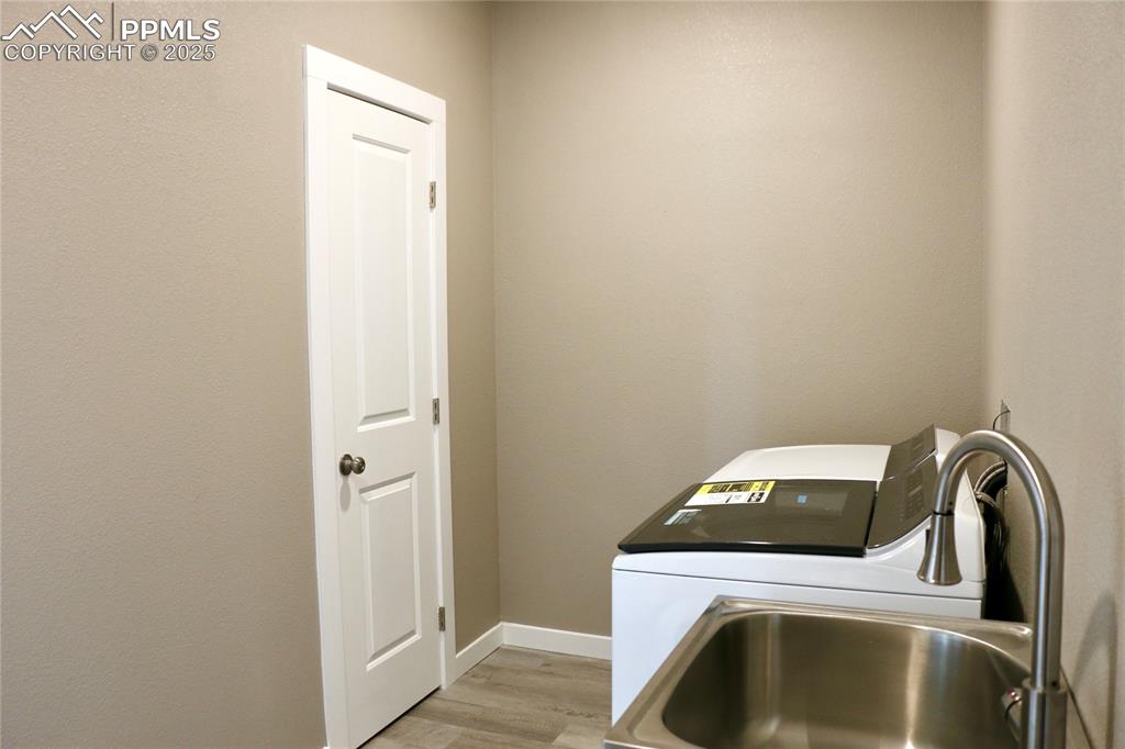 Image 17 of 28: Laundry area featuring baseboards and light wood-type flooring