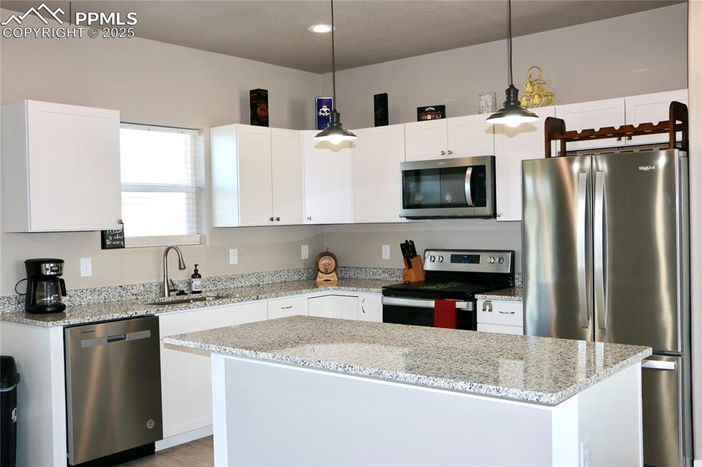 Image 19 of 28: Kitchen featuring stainless steel appliances, white cabinetry, decorative l