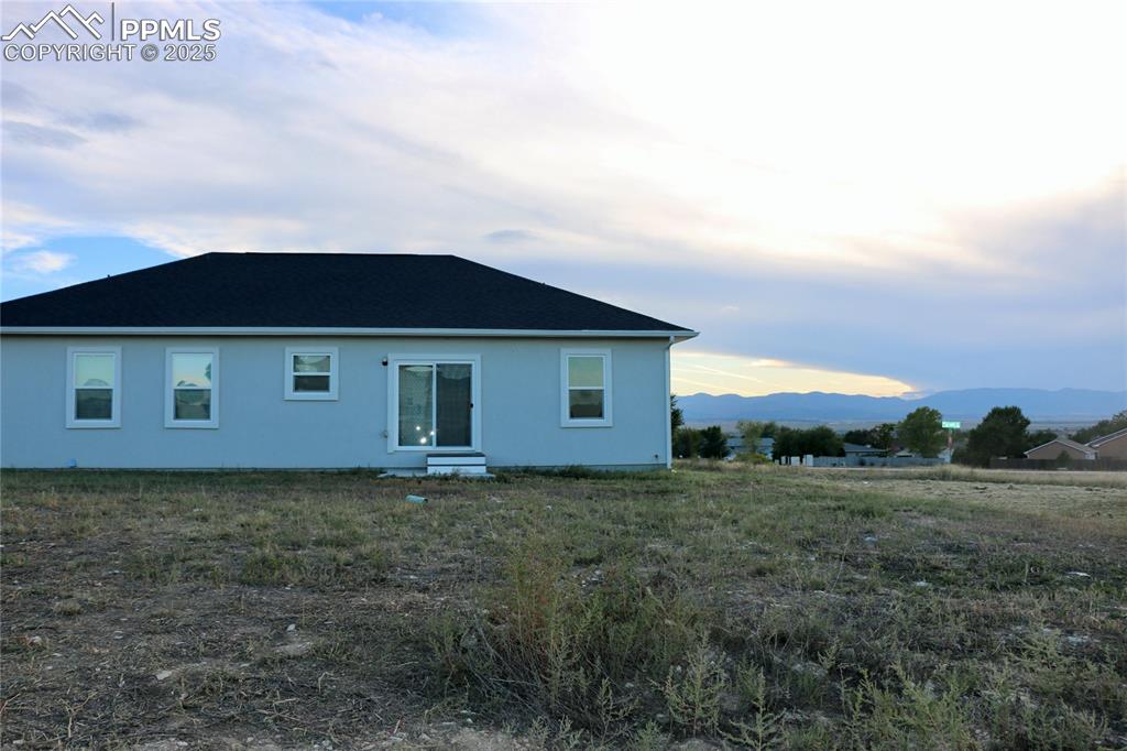 Image 26 of 28: Back of house featuring a mountain view and stucco siding