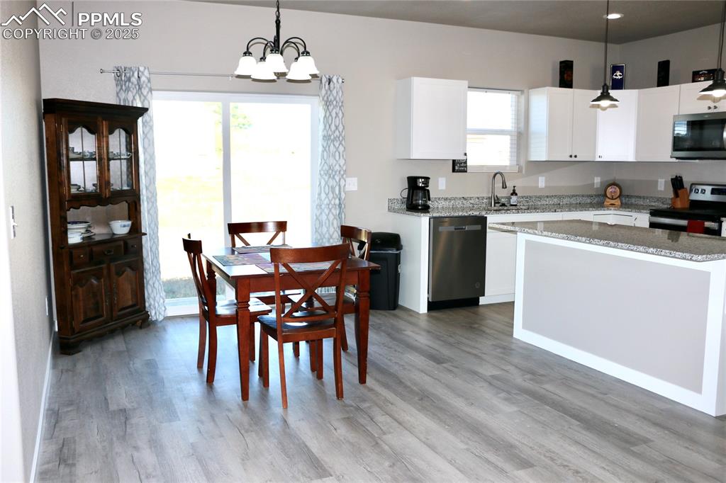 Image 3 of 28: Kitchen featuring hanging light fixtures, light stone counters, stainless s