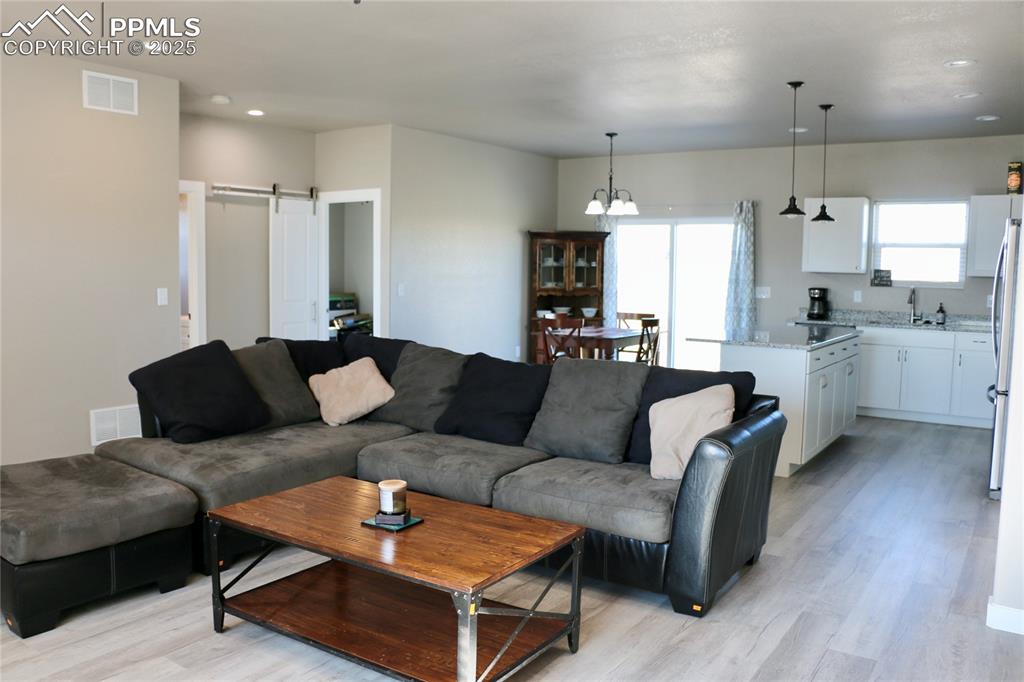 Image 5 of 28: Living room featuring a barn door, light wood finished floors, recessed lig