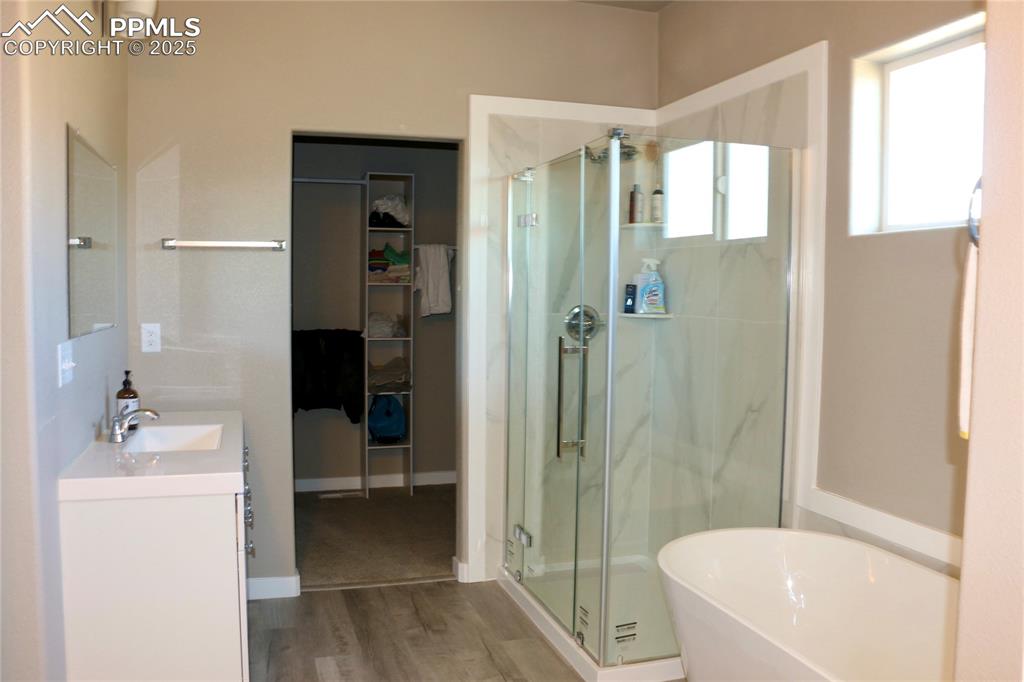 Image 8 of 28: Bathroom with a marble finish shower, vanity, a freestanding bath, wood fin