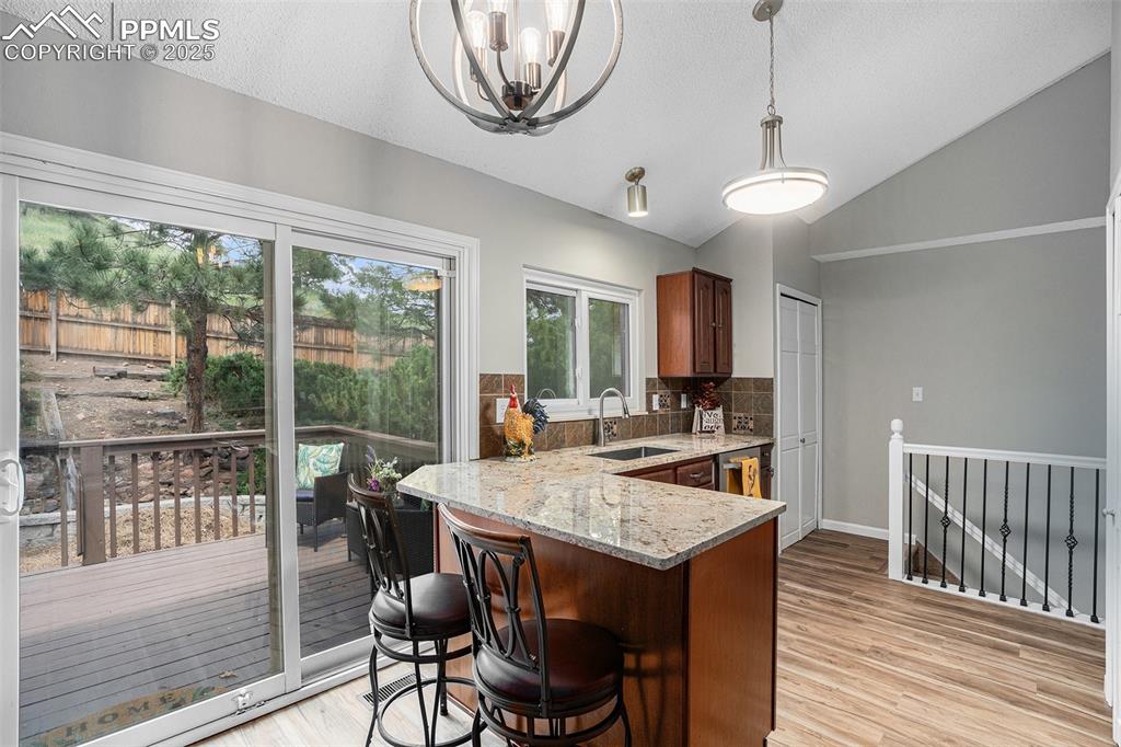 Image 13 of 34: Kitchen with lofted ceiling, tasteful backsplash, light wood-type flooring,
