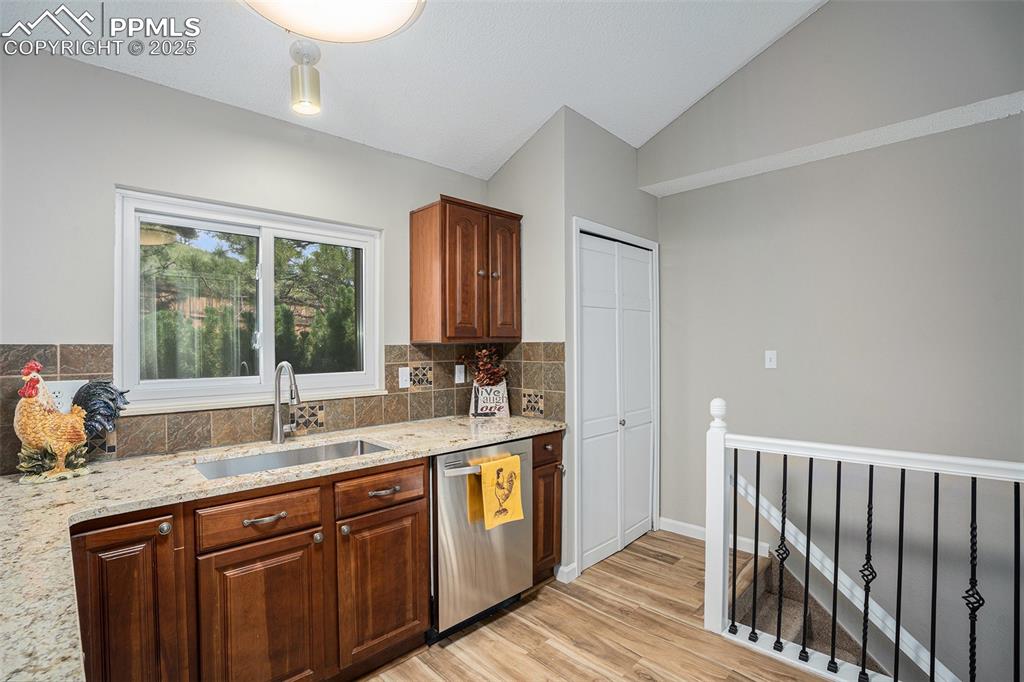 Image 15 of 34: Kitchen with vaulted ceiling, tasteful backsplash, stainless steel dishwash