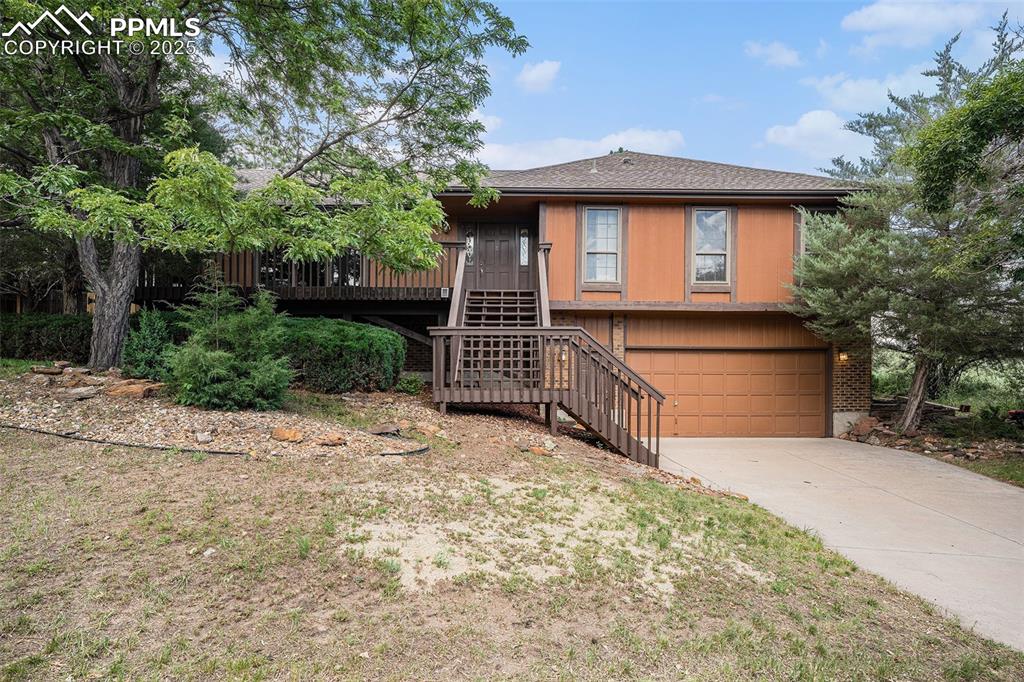 Image 2 of 34: View of front of home featuring stairs, a garage, driveway, and roof with s