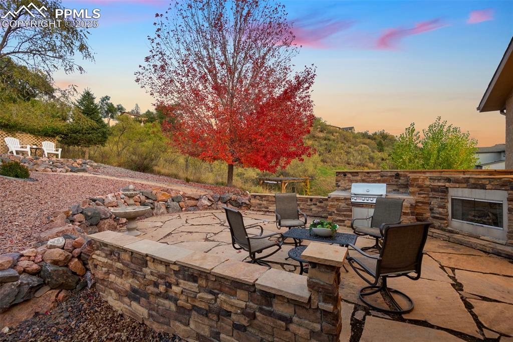 Image 15 of 47: Flagstone patio with built in grill and gas fireplace with additional view