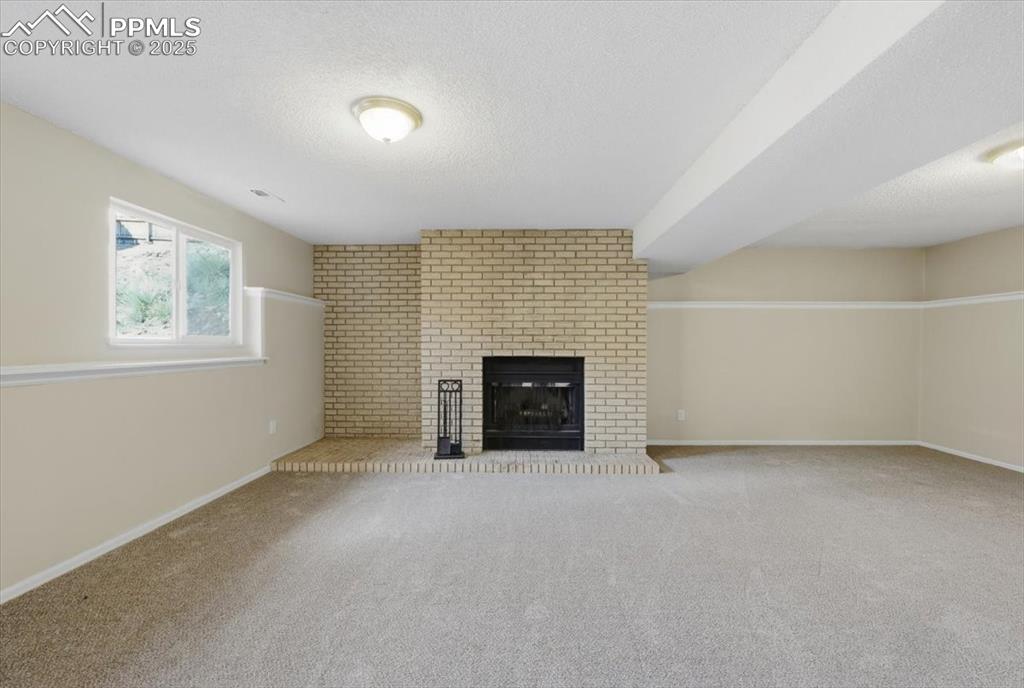 Image 37 of 47: Lower level family room with wood burning fireplace.