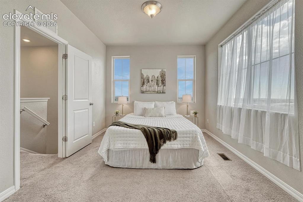 Image 21 of 40: Upper level Primary Bedroom with wall of windows, neutral carpet, adjoining