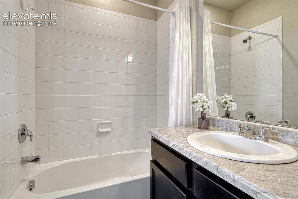 Image 23 of 40: Primary Bathroom with vanity, mirror, and tiled tub/shower.