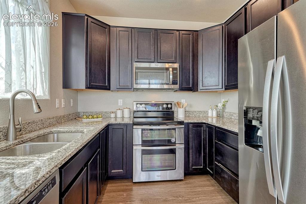 Image 4 of 40: The stylish Kitchen offers dark wood cabinets with granite countertops, and