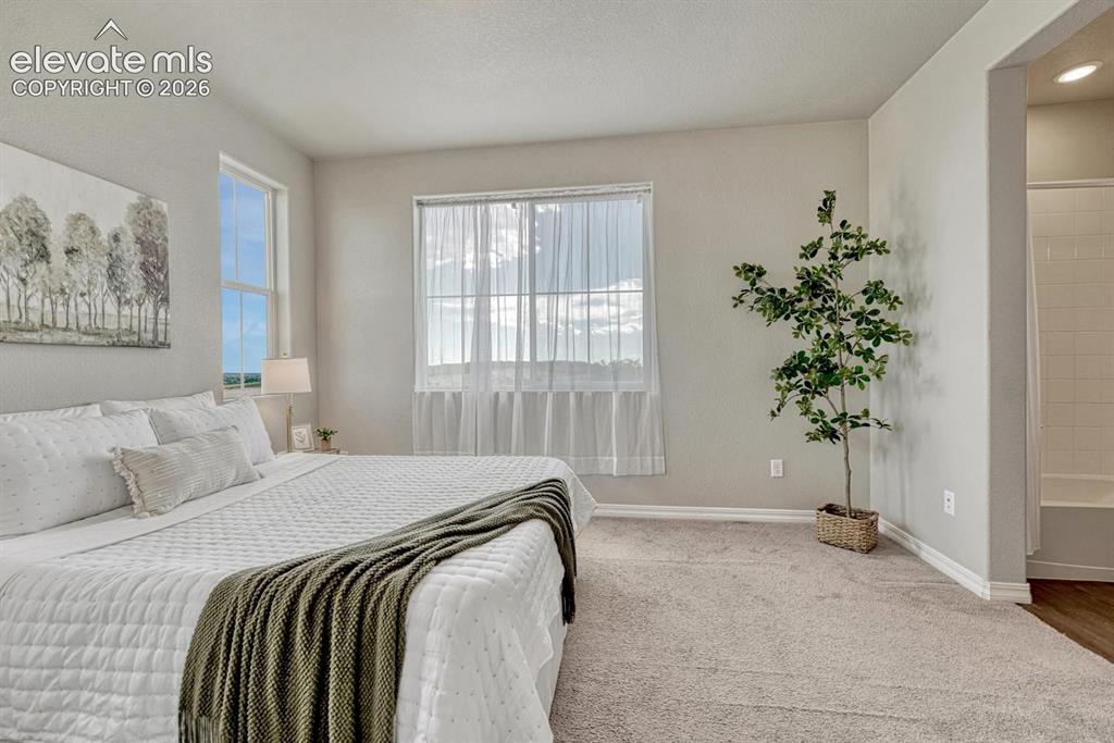 Image 5 of 40: The upper level Primary Bedroom features neutral carpet, an adjoining bathr
