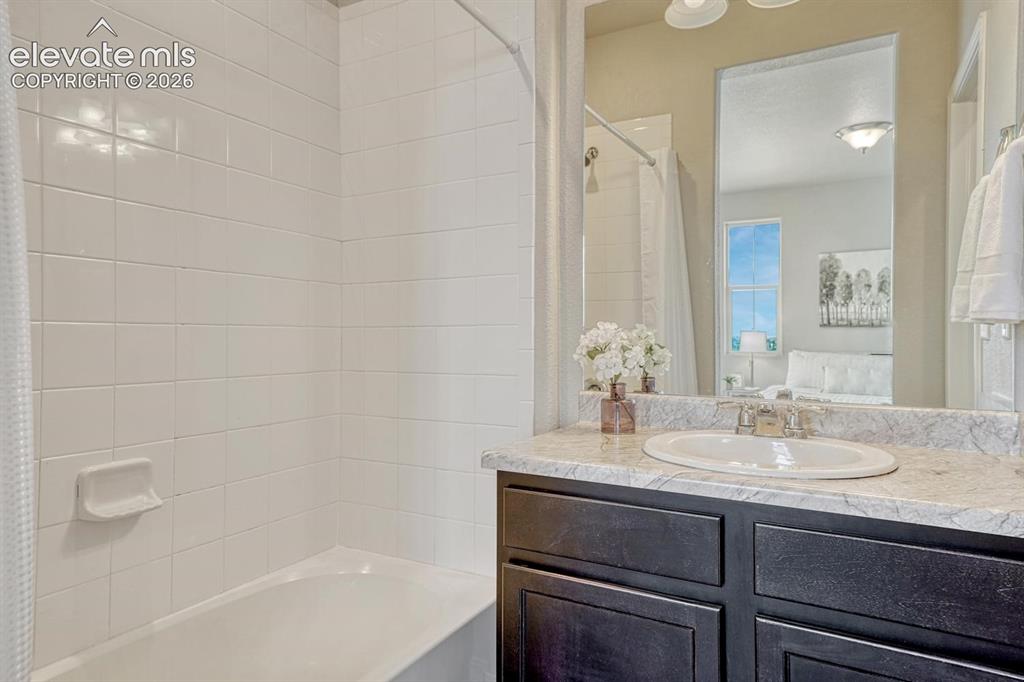 Image 6 of 40: The upper level Primary Bathroom boasts a vanity, mirror, and tiled tub/sho