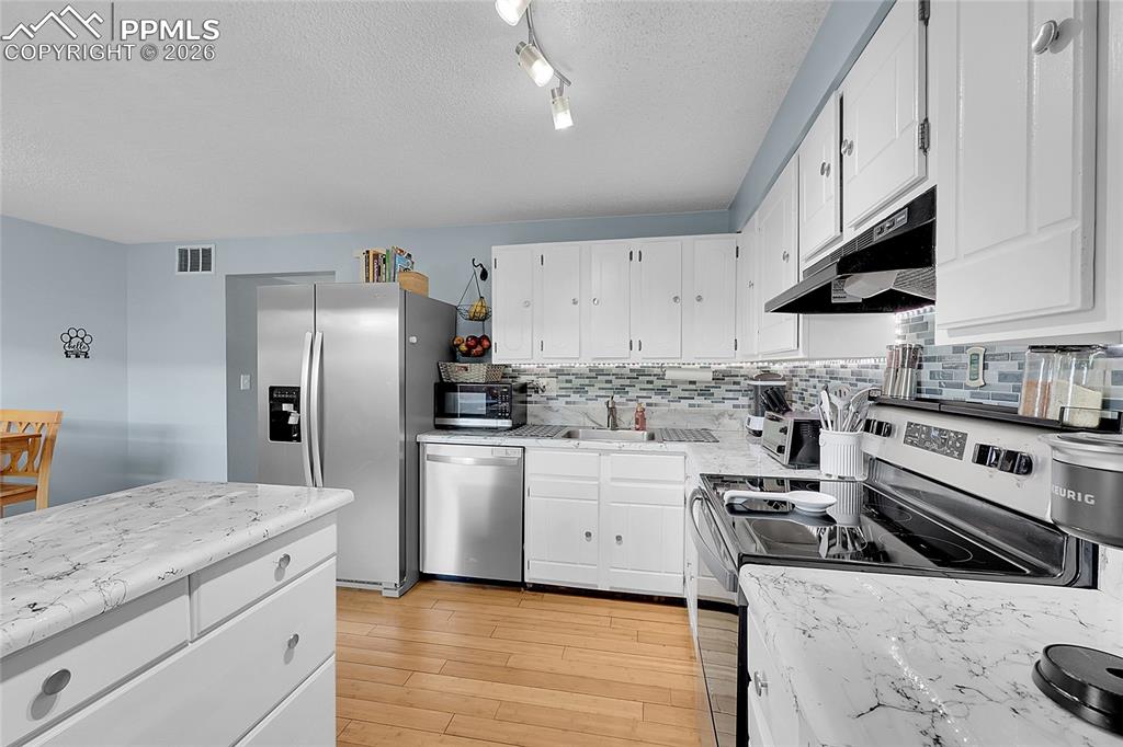 Image 6 of 30: Another view of kitchen with newer countertops and beautiful hardwood floor