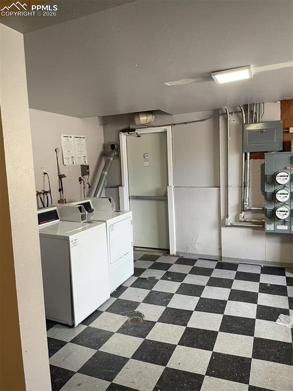 Image 28 of 29: Communal laundry room with electric panel and washing machine and dryer