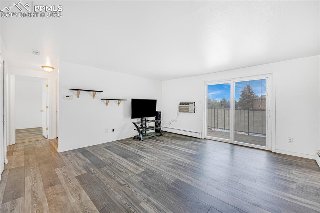 Image 4 of 29: Unfurnished living room featuring dark wood-type flooring and a baseboard r