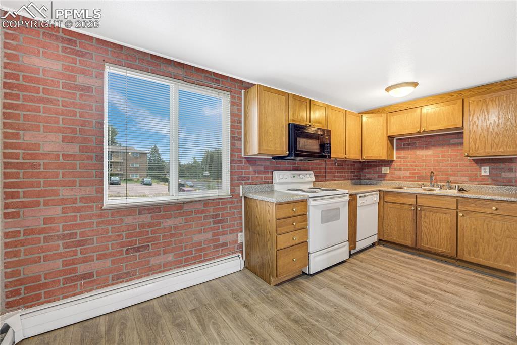 Image 8 of 29: Kitchen with a baseboard radiator, white appliances, light countertops, lig