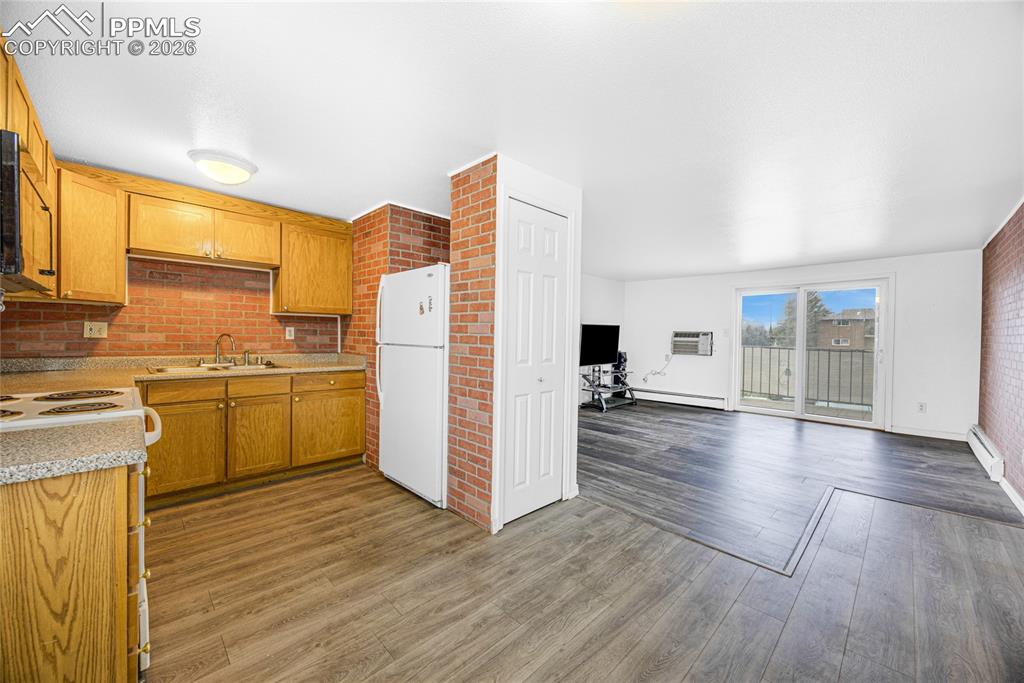 Image 9 of 29: Kitchen featuring light countertops, freestanding refrigerator, brick wall,