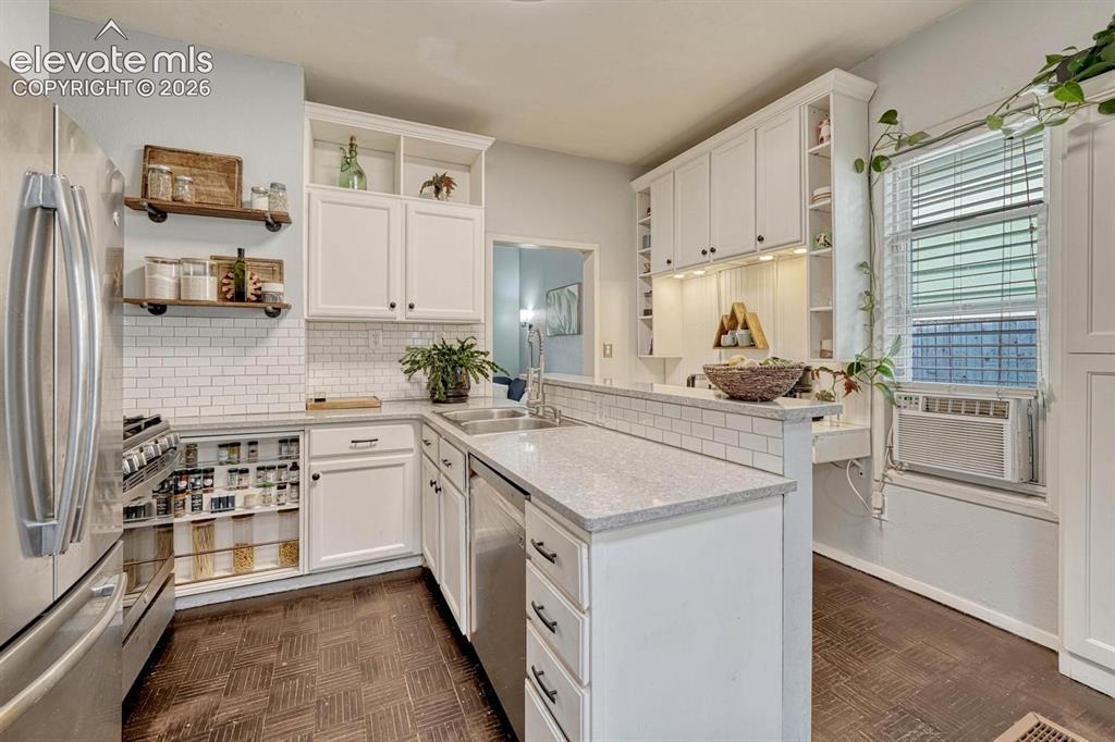 Image 10 of 50: Upgraded kitchen features white cabinets, gray granite counters, white mini