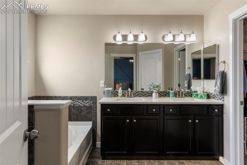 Image 11 of 32: Bathroom with double vanity, a bath, and a walk in closet