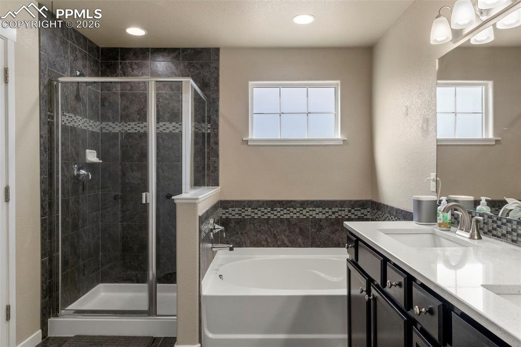 Image 12 of 32: Bathroom with double vanity, a shower stall, a bath, and recessed lighting