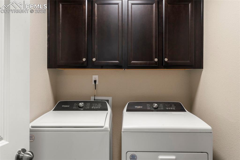 Image 21 of 32: Laundry room with separate washer and dryer and cabinet space