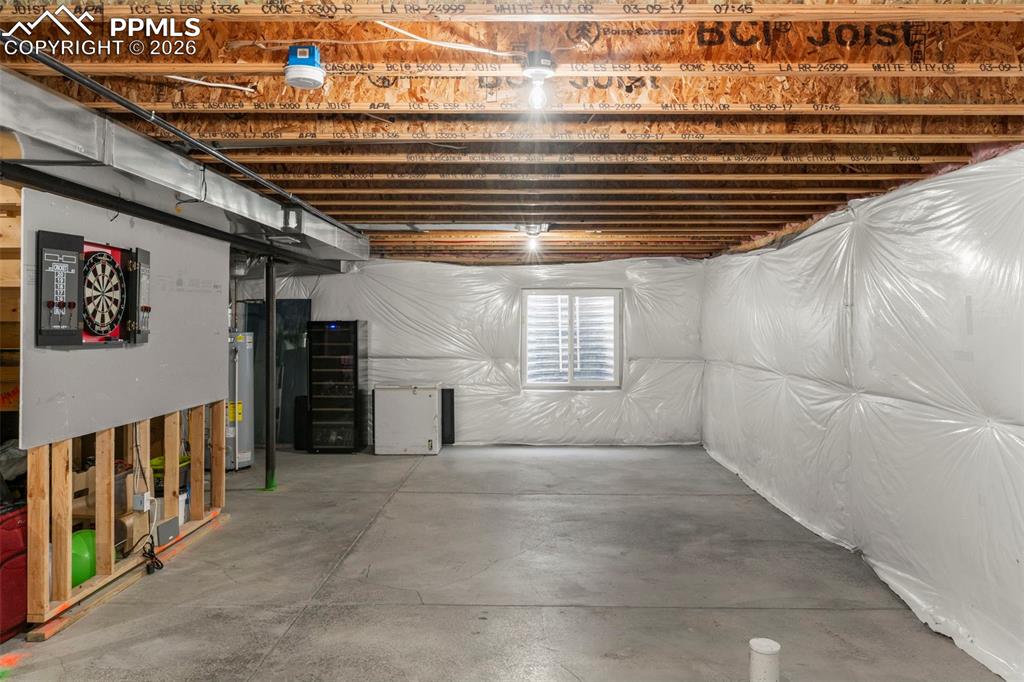 Image 24 of 32: Below grade area with white refrigerator and water heater