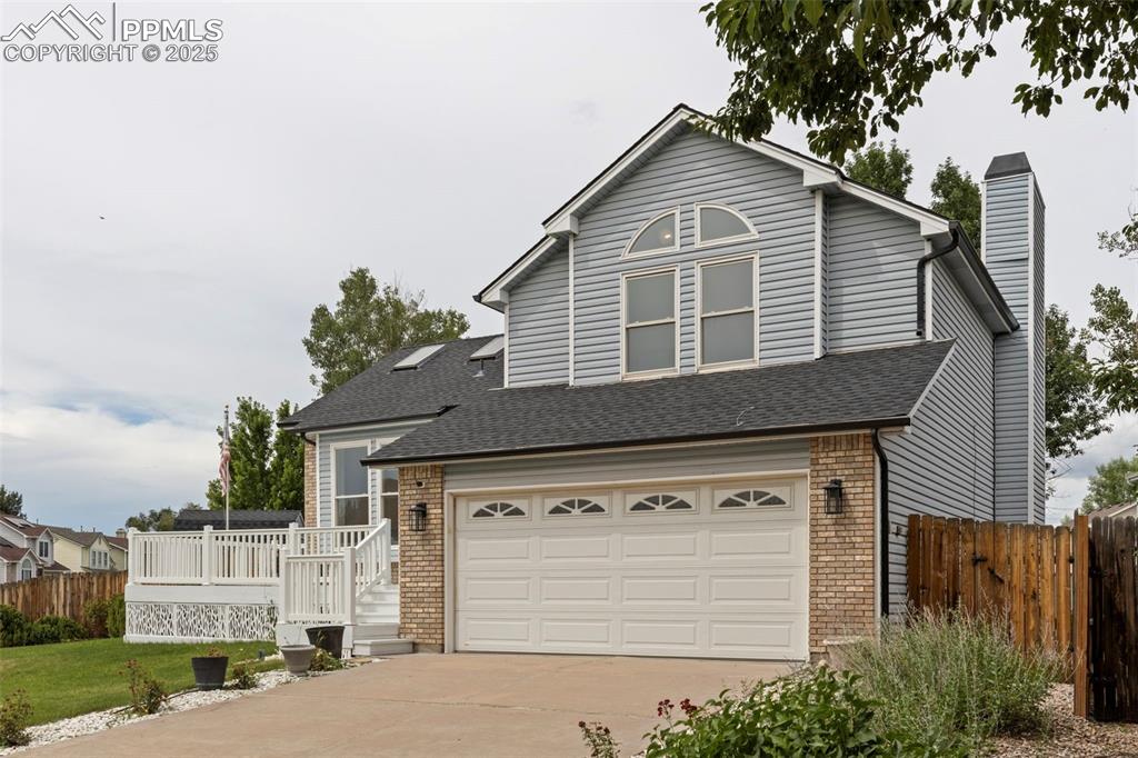 Caption: Traditional-style house featuring brick siding, a chimney, concrete driveway, an attached garage, an