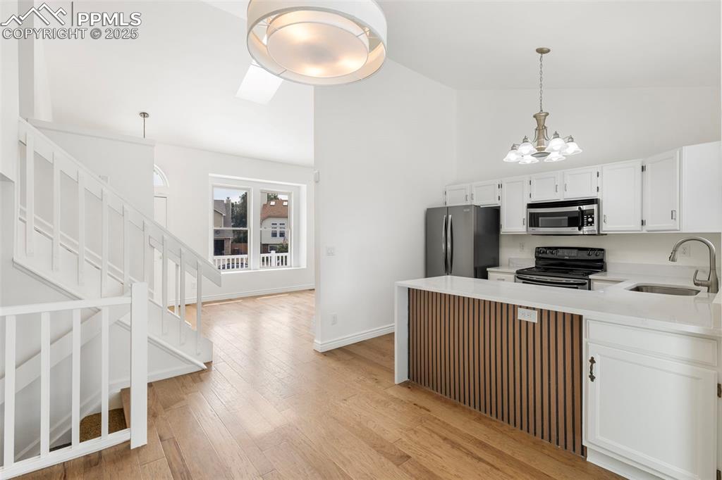Image 10 of 27: Kitchen with appliances with stainless steel finishes, light wood finished